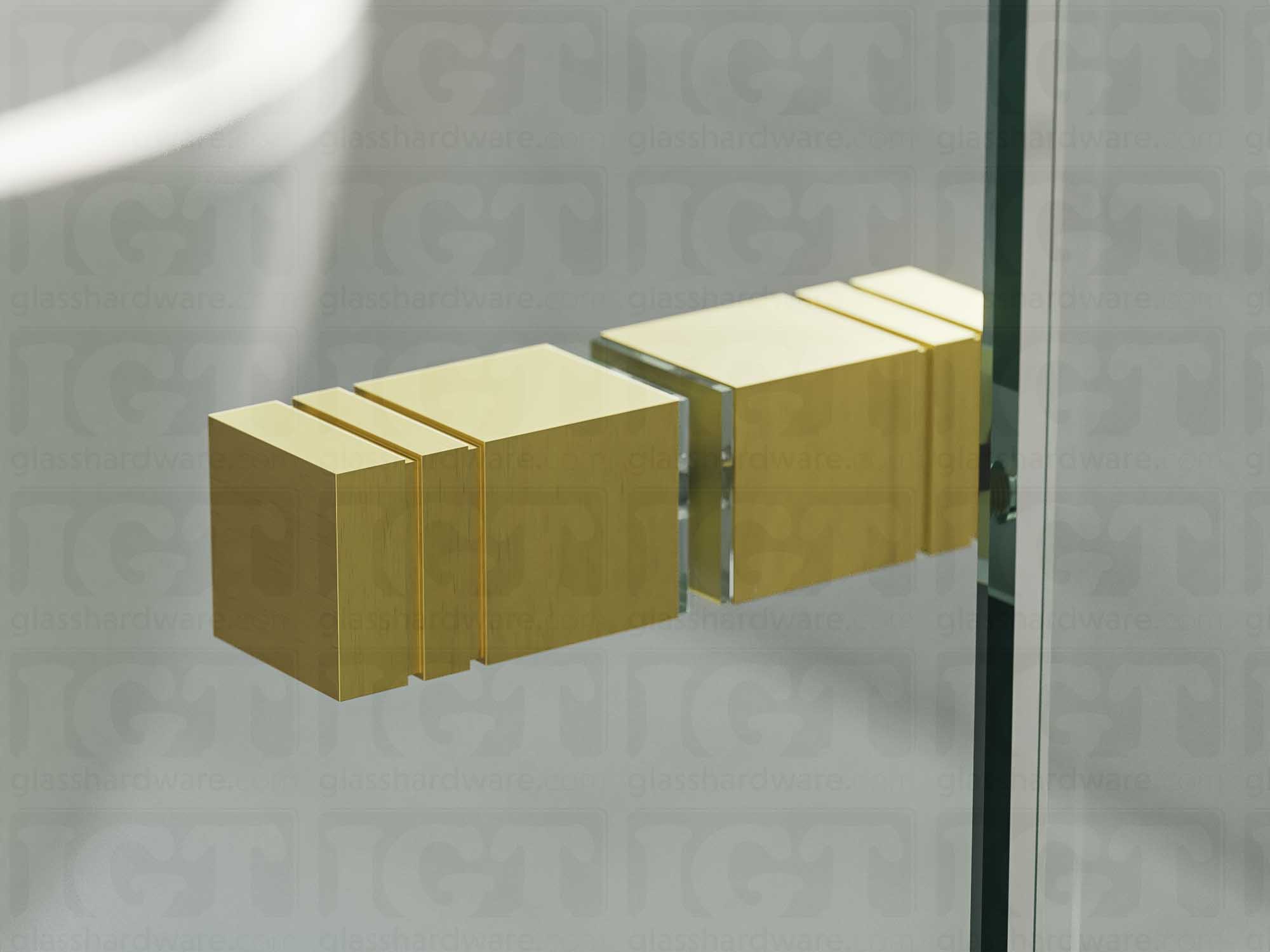 A close up of the Square Back-to-Back Door Knob installed on a glass shower door. Soft natural light highlights the knob's Gold Brushed finish.