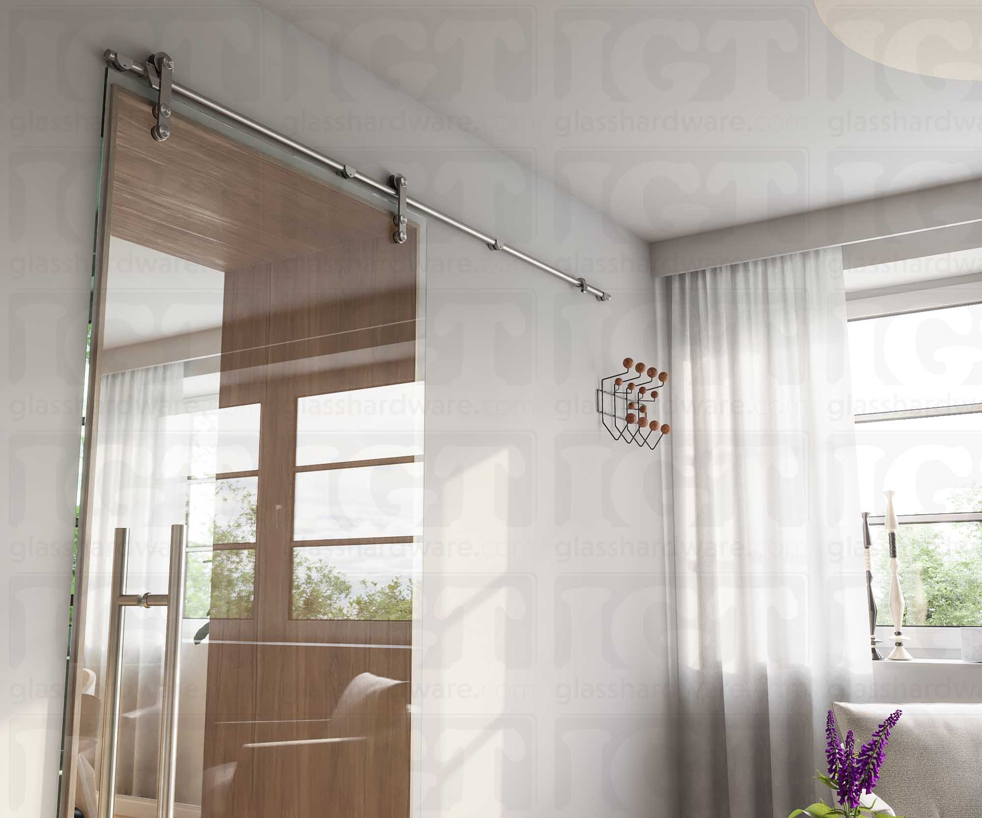 A modern living room featuring a glass barn door in the closed position, installed with four Wall Mount Brackets. Brushed Stainless.