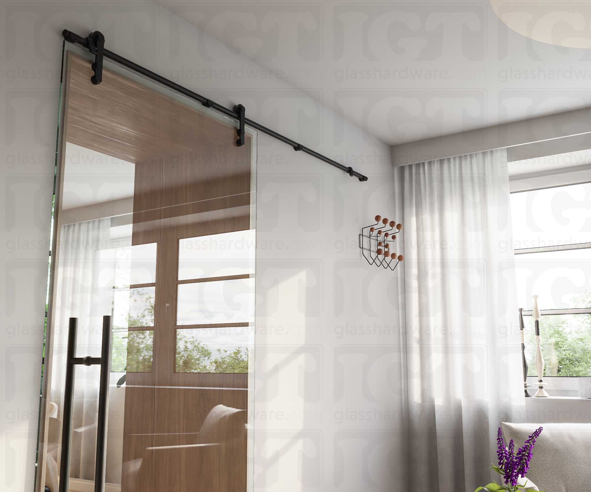 A modern living room featuring a glass barn door in the closed position, installed with four Wall Mount Brackets. Matte Black.