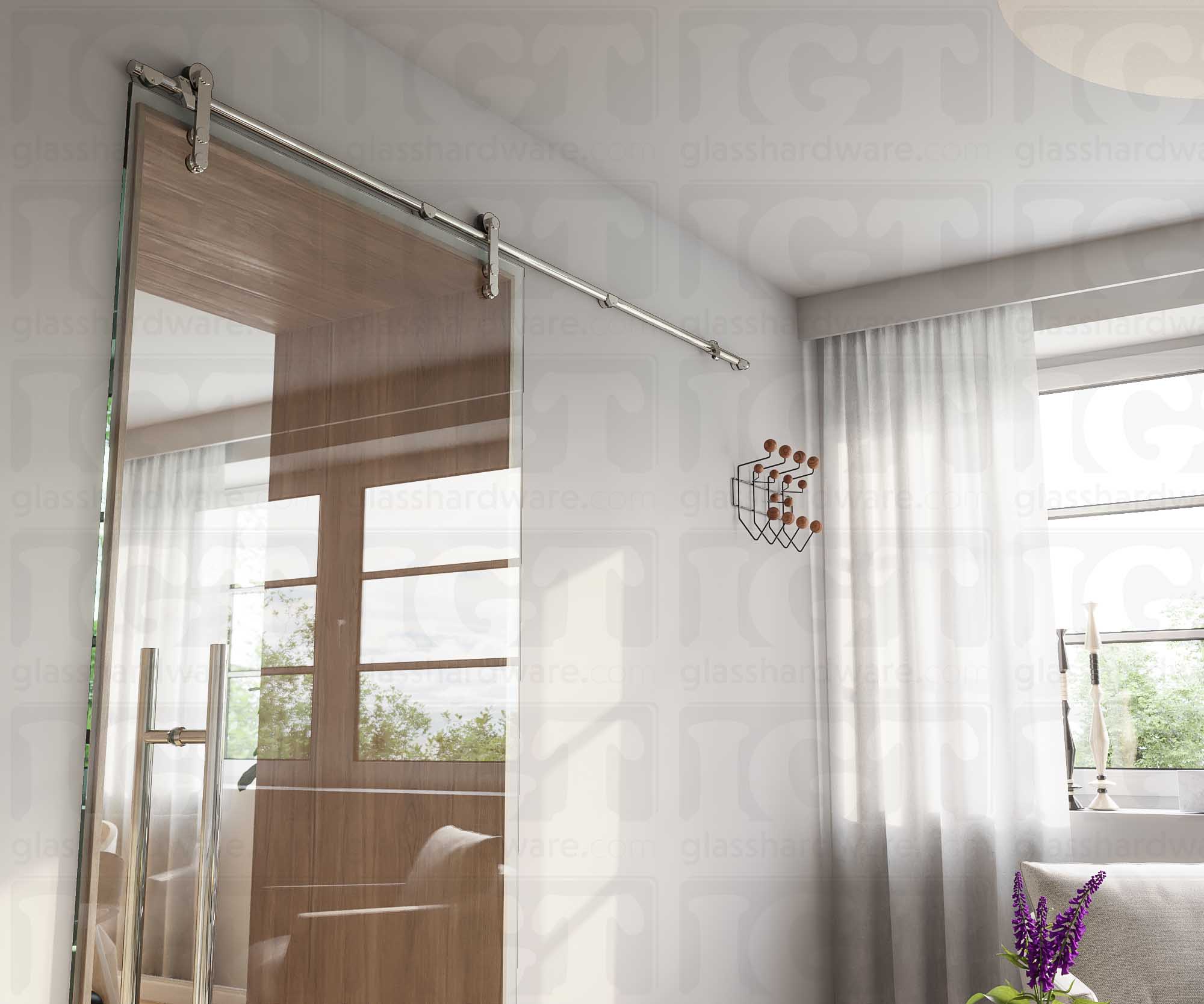 A modern living room featuring a glass barn door in the closed position, installed with four Wall Mount Brackets. Polished Stainless.