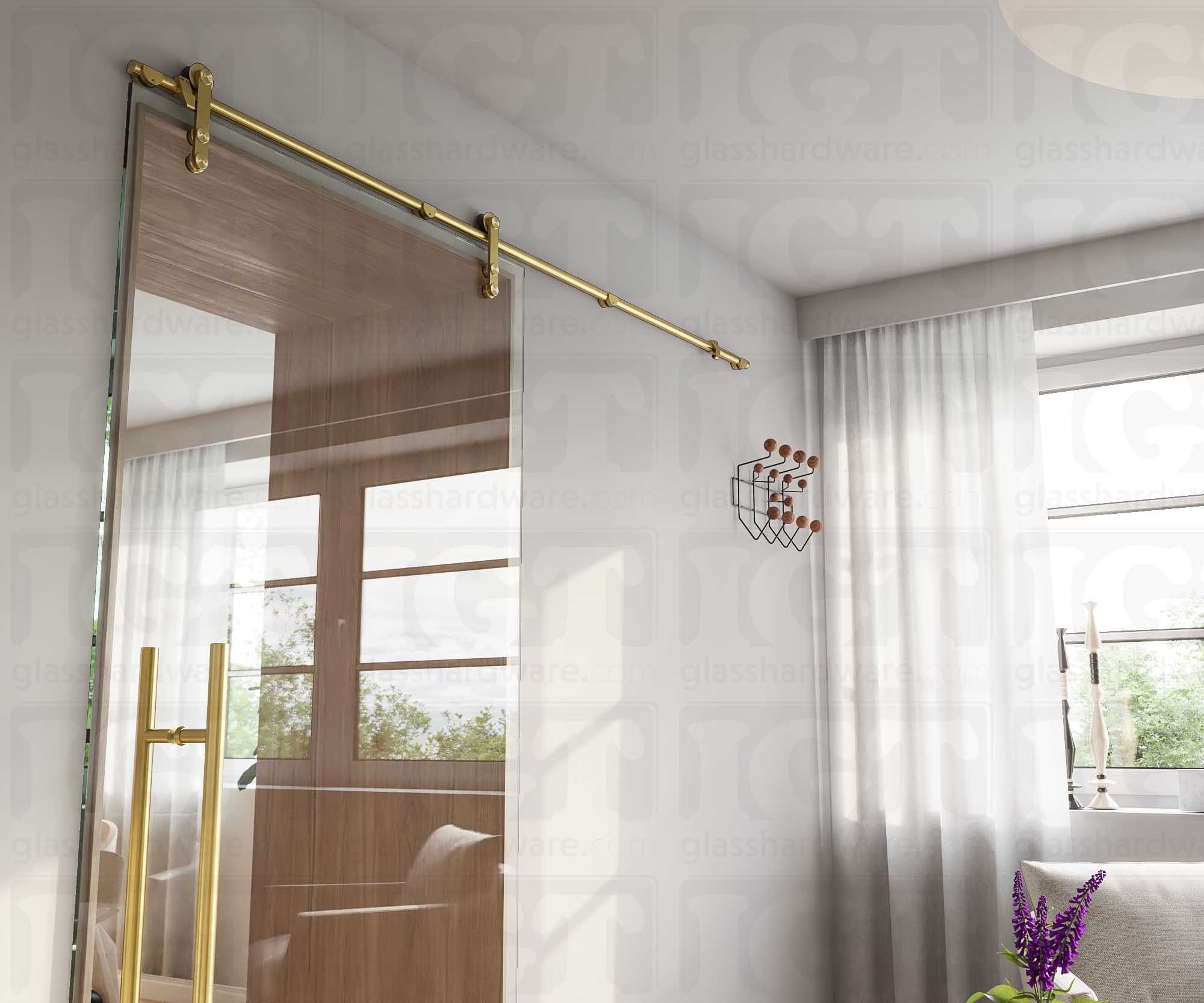 A modern living room featuring a glass barn door in the closed position, installed with four Wall Mount Brackets. Gold Brushed.