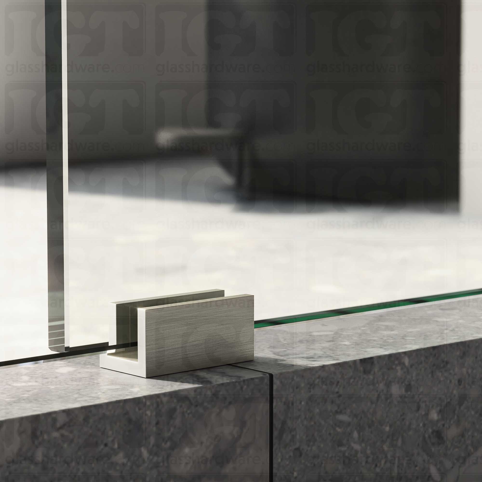 A close up of the Floor Guide for Modern Sliding System installed at the base of a glass sliding door, showcasing it's Brushed Nickel finish.