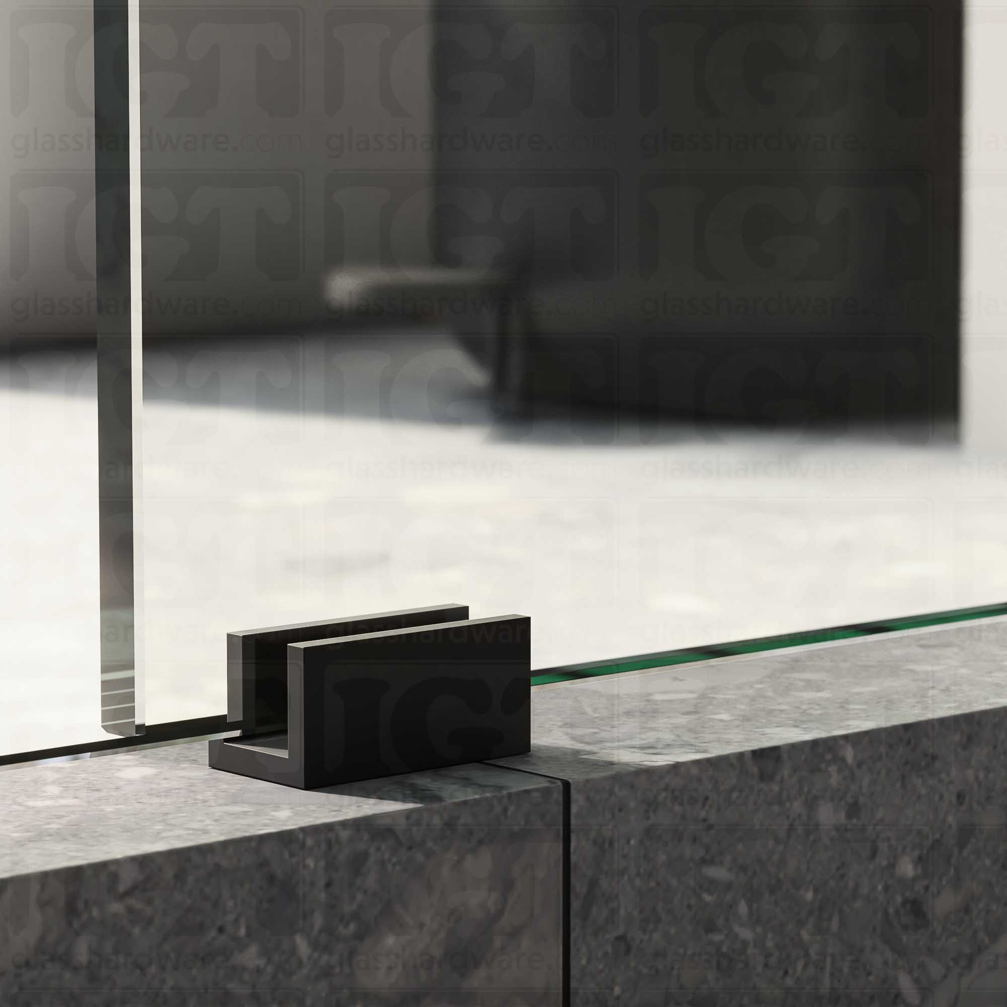 A close up of the Floor Guide for Modern Sliding System installed at the base of a glass sliding door, showcasing it's Matte Black finish.